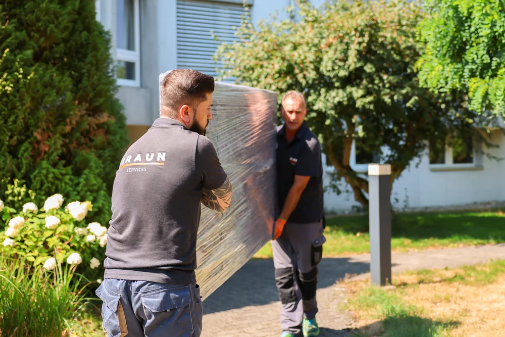 BRAUN-Mitarbeiter tragen gemeinsam ein geschütztes Möbelstück.