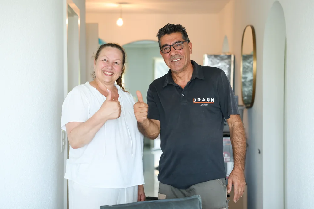Eine Kundin und ein BRAUN-Mitarbeiter lächeln nach dem Umzug.