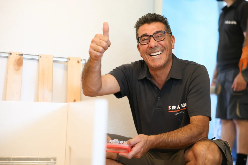 Ein lächelnder BRAUN-Mitarbeiter beim Packen eines Umzugskartons.